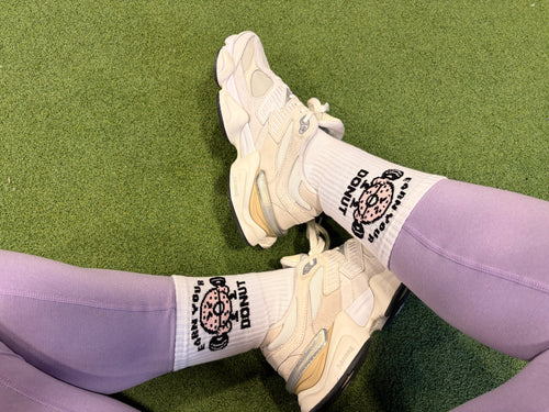 White sneakers and purple leggings with socks on a green grass background