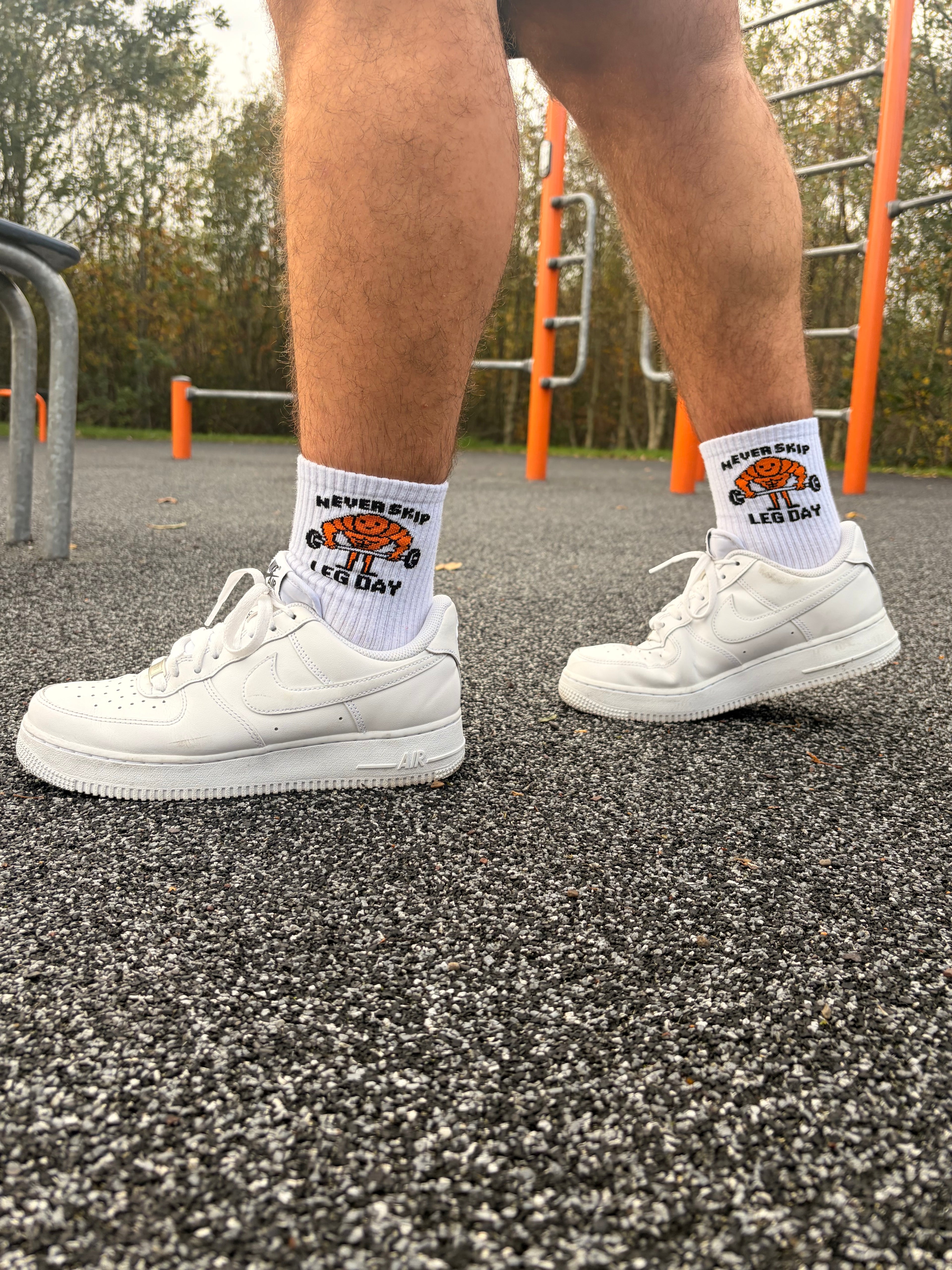 White sneakers and socks on a person standing on a road.