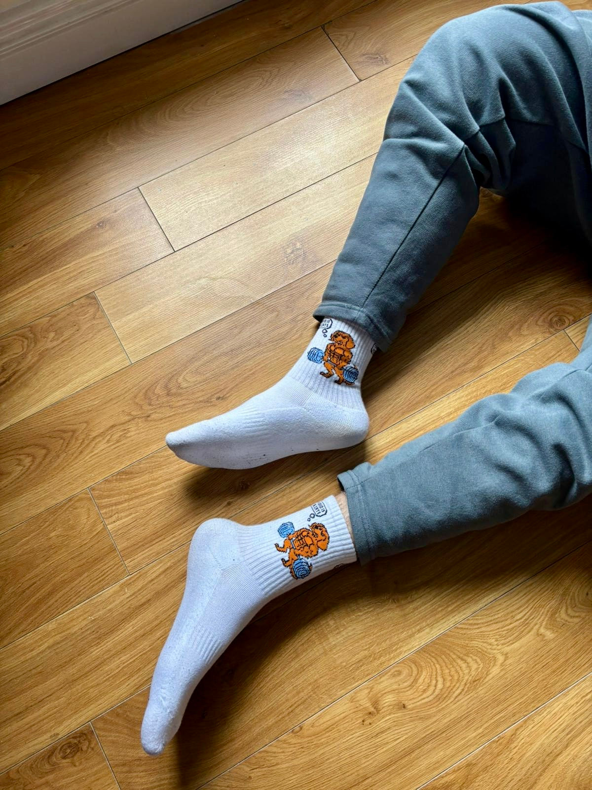 Person wearing white socks with cartoon characters on a wooden floor